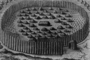 Black and white photograph of an engraving of a Native village with the chief's house in the center, surrounded by huts of other principal men, and fortified by a circular arrangement of tall palings that spiral to a narrow opening at the entrance. Engraved by Theodor de Bry.